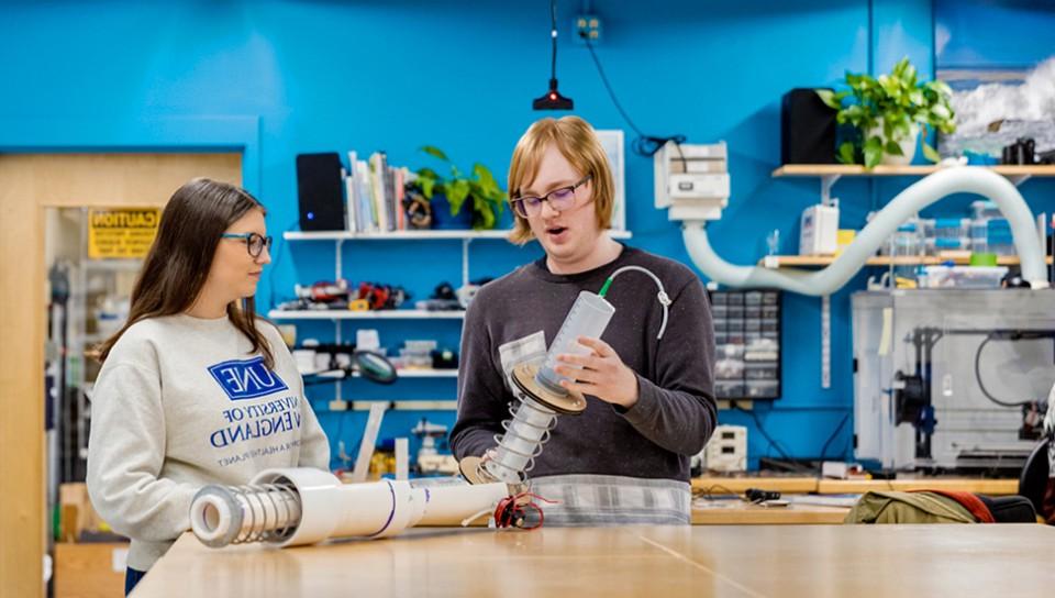 Two U N E students show their technology projects to one another in the Makerspace